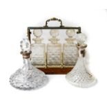An early 20th century oak and silver plated three bottle tantalus with three decanters and stoppers,