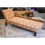 An Edwardian upholstered chaise longue raised on square spreading oak supports with brass castors,
