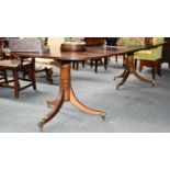 A 19th century mahogany twin pillar dining table with two additional leaves, with brass paw feet and