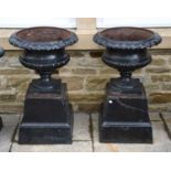 A pair of painted cast iron garden urns, with egg and dart moulding and raised on spreading square