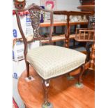 A small Edwardian mahogany nursing chair with carved back and re-covered seat on cabriole legs, with