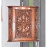 A 20th century hanging carved oak corner cupboard, decorated with foliate scrolls, 42cm by 26cm by