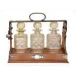 An early 20th century oak three bottle tantalus with silver plated mounts There is no key, frame