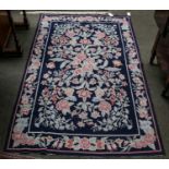 A Chinese needlepoint rug, the indigo field of semi-naturalistic floral sprays enclosed by floral