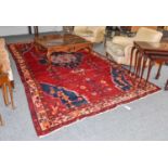 A Kurdish carpet, the crimson field centred by an indigo medallion and framed by ivory borders,