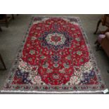 A Tabriz rug, probably reduced in size, the raspberry field of vines around a flower head