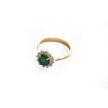 An emerald and diamond cluster ring, stamped '18CT', finger size K1/2The ring is in fair condition