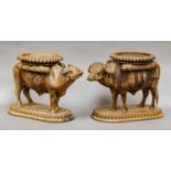 A pair of South East Asian carved stands formed as water buffalo, together with a brass three-draw