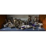 A collection of silver plated items including teasets, cake basket, salt sellers, etc (one shelf)