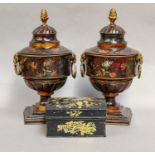 A pair of toleware pedestal mantel urns and covers, 19th century, with twin ram mask loop handles,