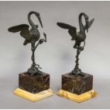 A pair of French patinated bronze sculptures, 19th century, each formed as a crane restraining a