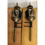 A pair of period style black painted and brass carriage lamps, with eagle mounts