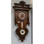 A striking wall clock circa 1890, the case with thermometer tube and aneroid barometer, the twin