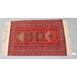 An Afghan Turkmen prayer rug, the brick red field with mosque enclosed by multiple borders, 137cm by