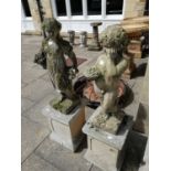 A pair of weathered composition garden statues of children holding flower baskets, on square section
