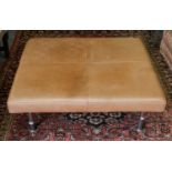 A tan leather oversized footstool, 101cm square by 34cm