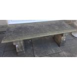 A composition stone bench, the moulded rectangular seat on two scrolled supports, 129cm by 40cm by