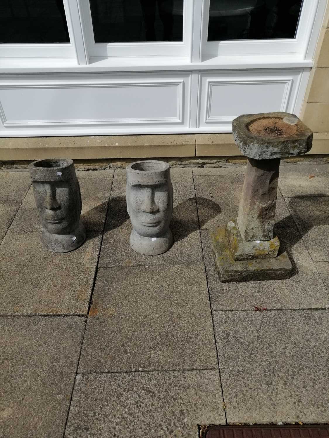 A weathered stone bird bath, together with two composition Easter Island heads (2)