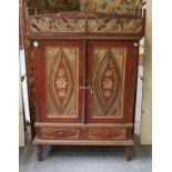A South East Asian painted and parcel gilt two door cabinet, carved with foliate and floral