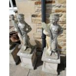 A pair of weathered composition garden statues of children holding wheat sheafs, on square section