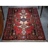 A tribal rug, raspberry field with ivory medallions, 146cm by 105cm