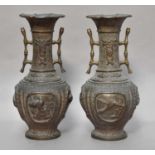 A pair of early 20th century Japanese bronze vases, decorated with relief work panels depicting