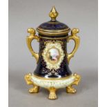 A Coalport twin handled urn and cover raised on paw supports, ground in cobalt blue, pale yellow and