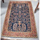 Sarouk Rug, the indigo field of leafy boughs enclosed by terracotta borders of meandering vines,