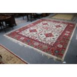An Indian Carpet, the ivory stepped lattice field enclosed by crimson borders, 370cm by 290cm