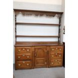 An Oak Dresser and Rack, 18th century, the inverted breakfront base with a central arch panel door