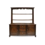 A Mid 18th Century Oak Enclosed Dresser and Rack, the upper section with a wavy shaped apron above