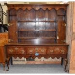 A Late George III Oak Dresser and Rack, with scrolling brass strapwork, carved apron and pad feet,