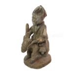 A Yoruba Carved Wood Figure, Nigeria, as a man seated astride a horse, on an oval plinth with