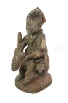 A Yoruba Carved Wood Figure, Nigeria, as a man seated astride a horse, on an oval plinth with