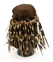 A Kaka Ceremonial Porcupine Quill Hat, Cameroon, the coarsly woven brown cloth body decorated with