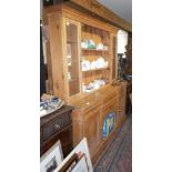 Pine kitchen dresser with upper section of shelves and glass fronted cabinet above four drawers