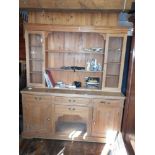Pine kitchen dresser with upper section of shelves and glass fronted cabinet above four drawers