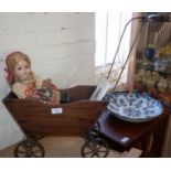 Antique wood and metal four wheeled doll's pushchair, a composition doll in Russian costume and a