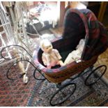 Vintage wickerwork child's dolls carriage on four wheels with hood and lined with tartan fabric