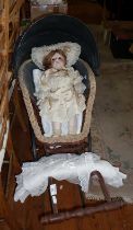 Wickerwork and steel two-wheeled doll's carriage with porcelain headed doll