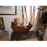 Antique wood and metal four wheeled doll's pushchair, a composition doll in Russian costume and a