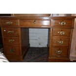 Light oak kneehole pedestal desk of nine drawers with tooled green leather top and having brass