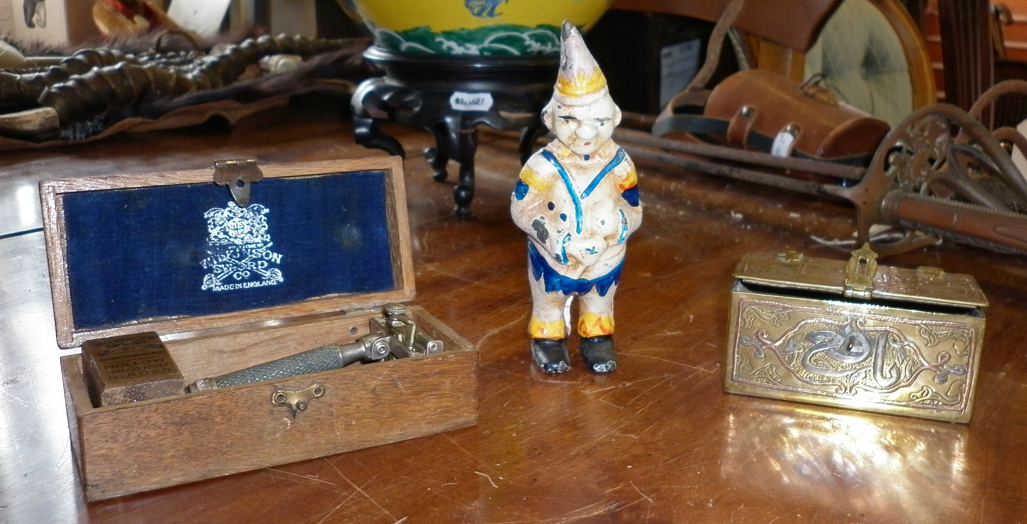 Painted cast iron clown money box, small Persian brass casket and a Wilkinson Sword safety razor,