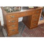 Light oak kneehole pedestal desk of nine drawers with tooled green leather top and having brass