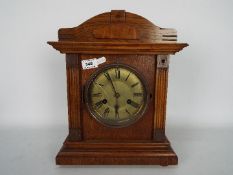 A wood cased mantel clock of architectural form, with key and pendulum.