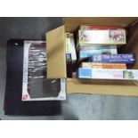 A collection of boxed jigsaw puzzles and three portable jigsaw puzzle boards.