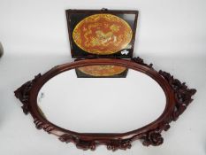 A Chinese hardwood framed mirror, 90 cm x 53 cm and a framed embroidery depicting a Buddhist lion.