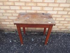 A vintage wooden school desk with hinged top and inkwell recess,