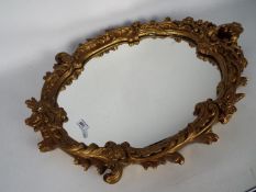 An ornately framed oval wall mirror, 69 cm x 51 cm.