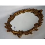 An ornately framed oval wall mirror, 69 cm x 51 cm.